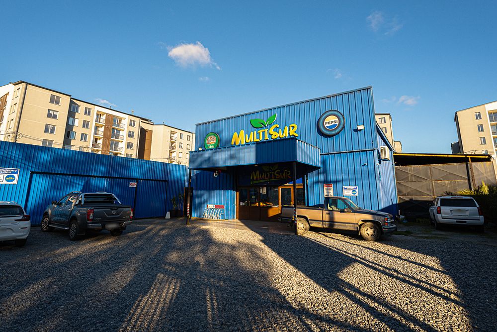 Fachada del galpón azul de Multisur y su estacionamiento